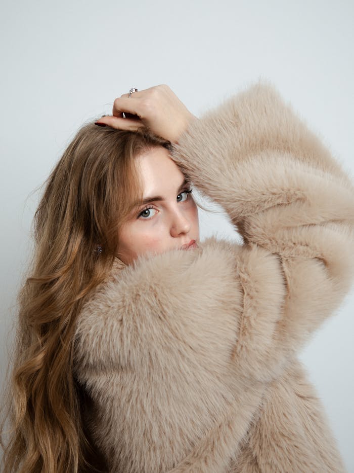 Portrait of a stylish woman wearing a soft beige fur coat, showcasing elegance and sophistication.